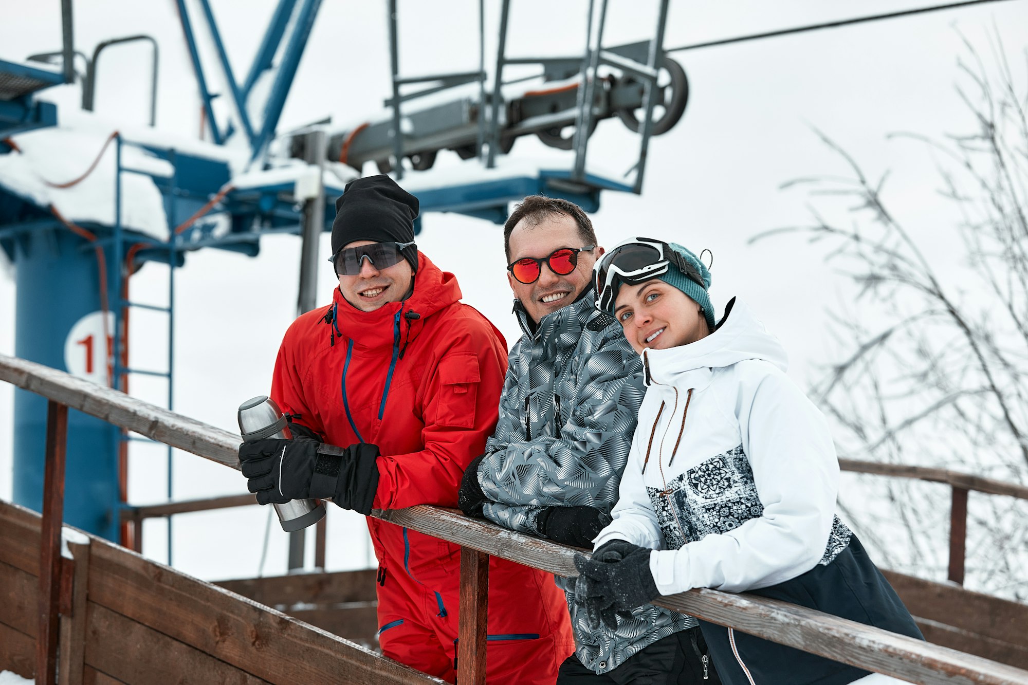 group of skiers friends on the mountain are resting and drinking coffee from a thermos on the
